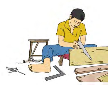 Man in a yellow shirt and blue pants sitting on the floor using a saw to cut a wooden plank, surrounded by carpentry tools and wooden pieces, focused and calm atmosphere in a simple indoor workspace